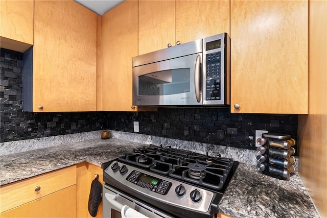 kitchen featuring dark stone counters, appliances with stainless steel finishes, and decorative backsplash
