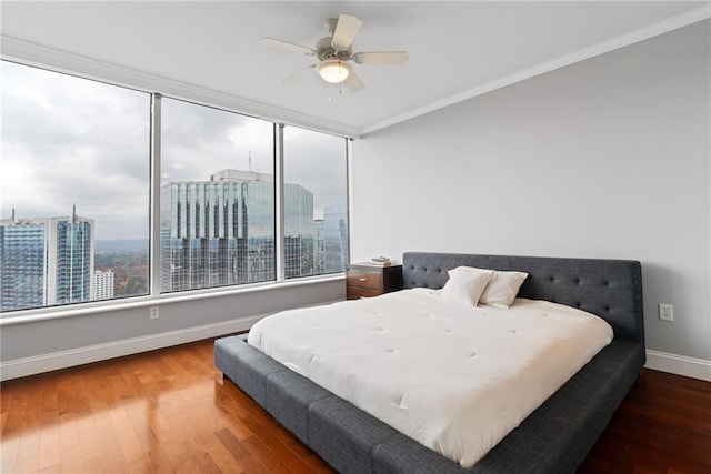bedroom featuring crown molding, baseboards, a city view, and wood finished floors