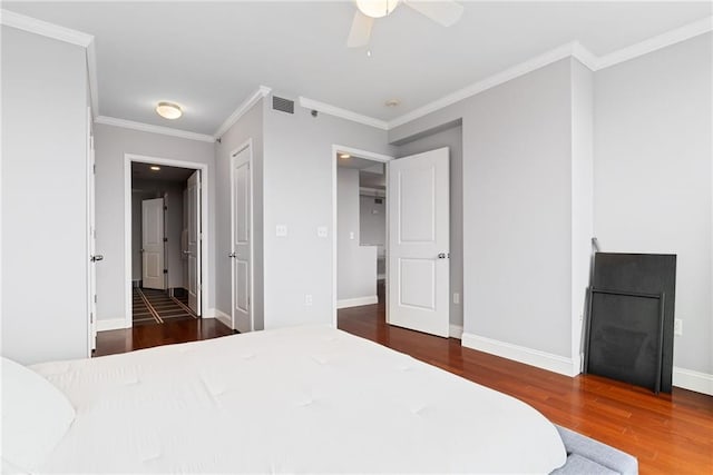 bedroom with visible vents, baseboards, crown molding, and wood finished floors
