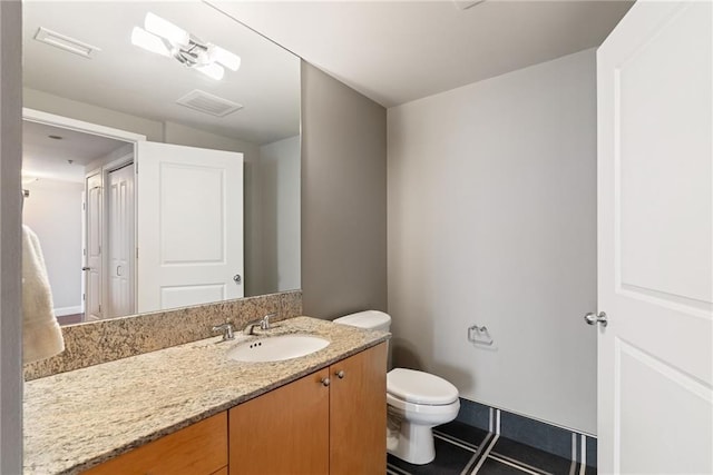 bathroom with toilet, visible vents, and vanity