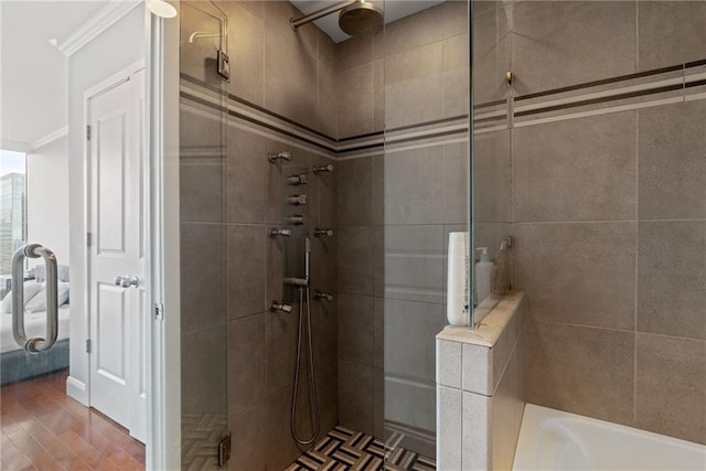 bathroom featuring ornamental molding, a shower stall, and wood finished floors