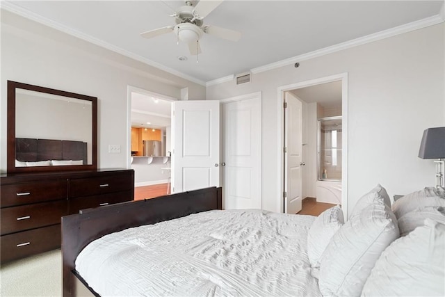 bedroom with crown molding, freestanding refrigerator, baseboards, ensuite bathroom, and visible vents