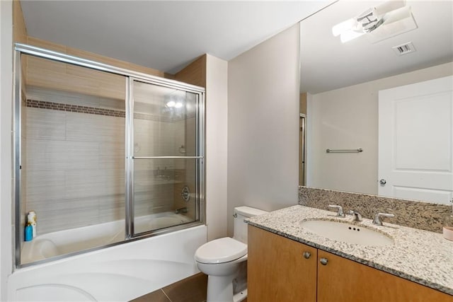 bathroom featuring vanity, combined bath / shower with glass door, visible vents, and toilet