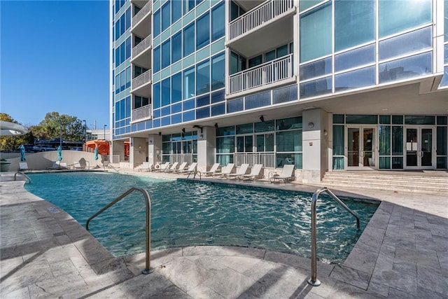 community pool with french doors and a patio