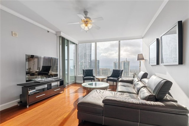 living area with ornamental molding, light wood-style flooring, ceiling fan, and a wealth of natural light