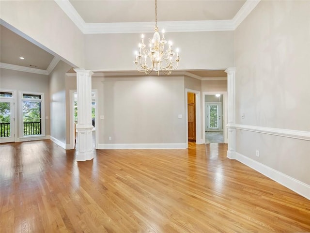 interior space featuring baseboards, ornamental molding, a chandelier, decorative columns, and light wood finished floors