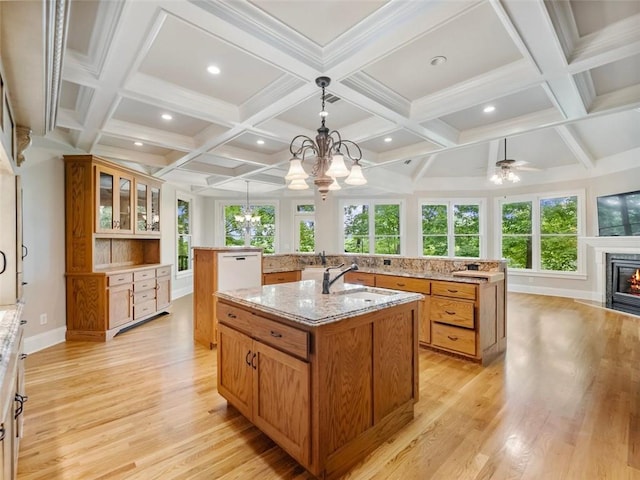 kitchen with brown cabinets, a healthy amount of sunlight, a sink, and a spacious island