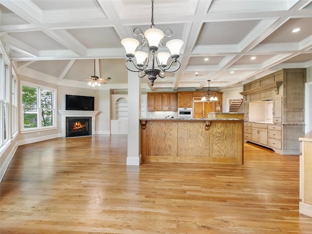 kitchen with white oven, a peninsula, a warm lit fireplace, open floor plan, and light wood finished floors