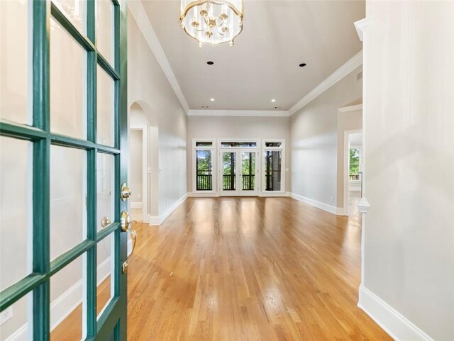 unfurnished living room with french doors, light hardwood / wood-style flooring, a notable chandelier, and ornamental molding