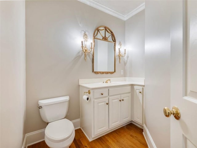 bathroom with crown molding, vanity, toilet, wood finished floors, and baseboards