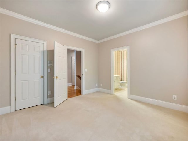 unfurnished bedroom featuring crown molding, ensuite bathroom, baseboards, and light carpet