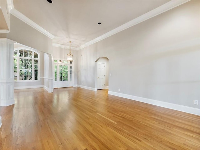 interior space with arched walkways, baseboards, ornamental molding, and light wood-type flooring