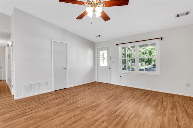 empty room with vaulted ceiling, visible vents, and light wood-type flooring