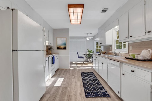 kitchen with white appliances, white cabinets, light wood-style floors, and visible vents