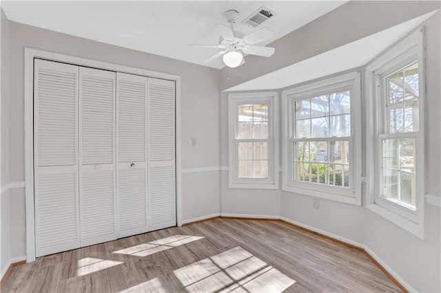 unfurnished bedroom featuring visible vents, baseboards, wood finished floors, a closet, and a ceiling fan