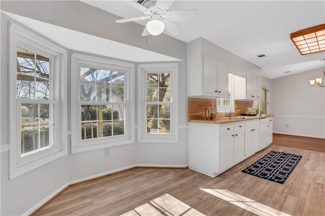 kitchen with a healthy amount of sunlight, white cabinets, light countertops, and light wood-style floors