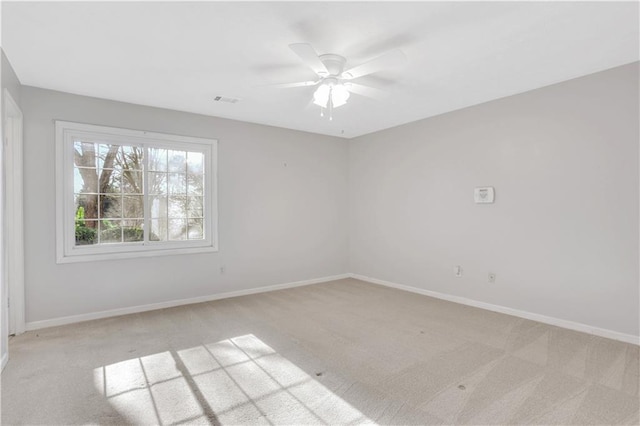 spare room with visible vents, light colored carpet, a ceiling fan, and baseboards