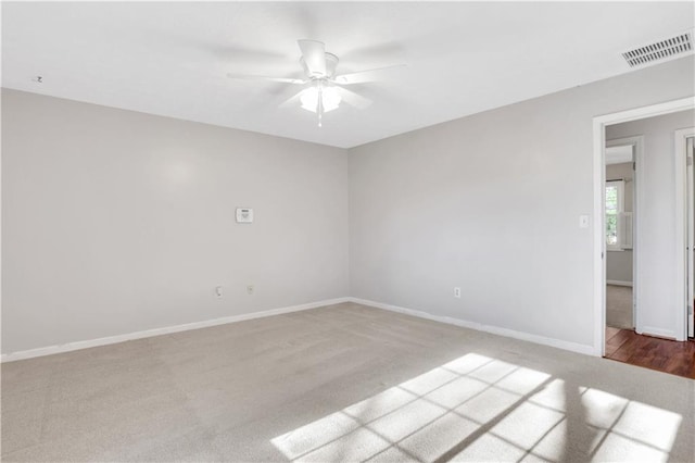 carpeted spare room featuring a ceiling fan, baseboards, and visible vents