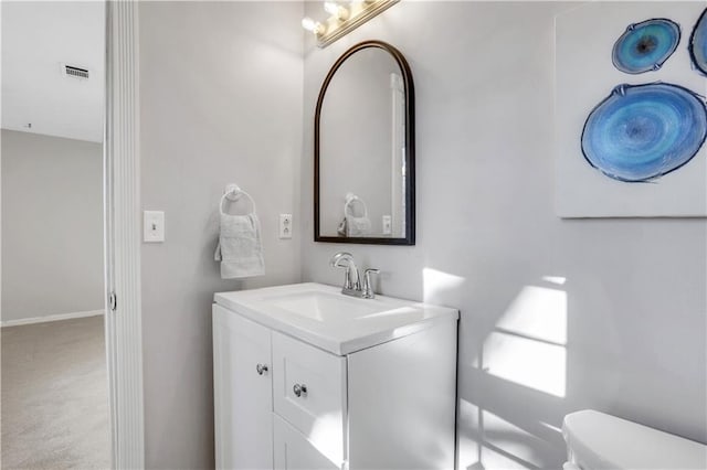 half bath featuring vanity, toilet, and visible vents