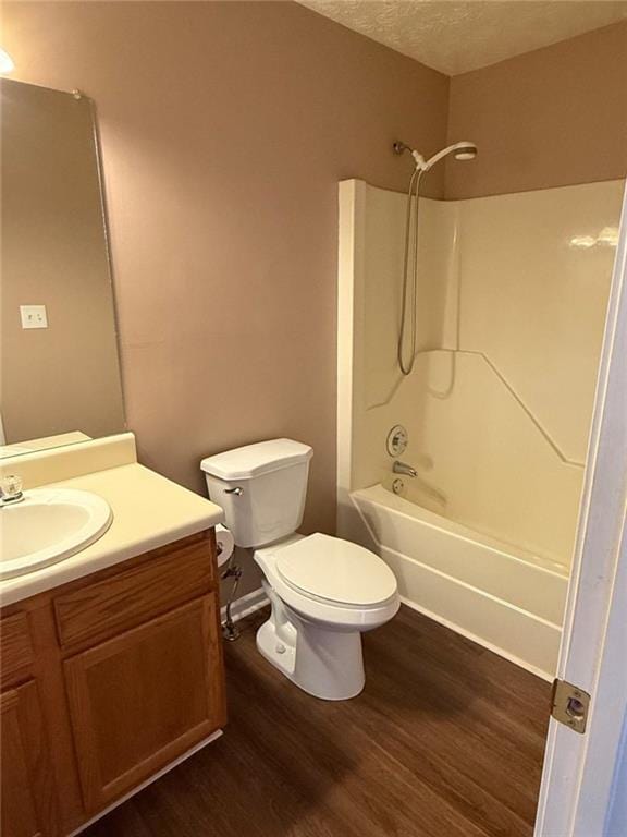 full bath featuring a textured ceiling, shower / bathtub combination, toilet, wood finished floors, and vanity