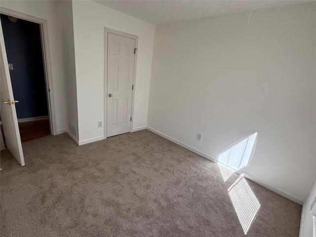 unfurnished bedroom with carpet floors, visible vents, and baseboards