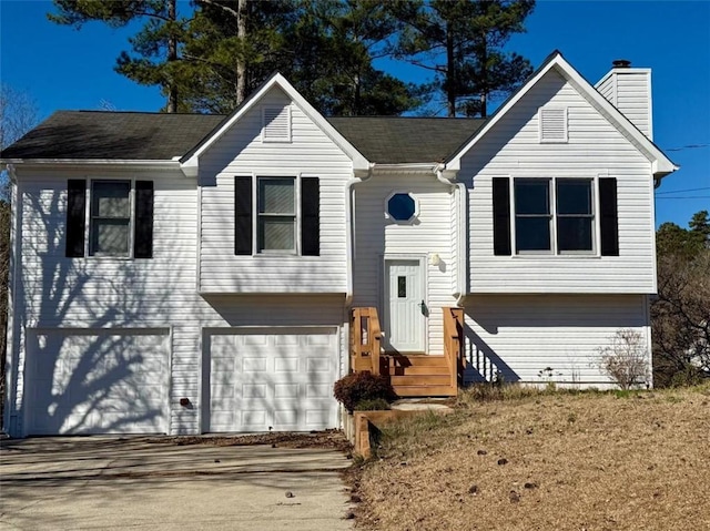 split foyer home featuring entry steps, driveway, a chimney, and an attached garage