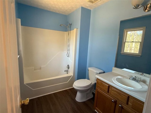 bathroom with a textured ceiling, shower / tub combination, toilet, wood finished floors, and vanity