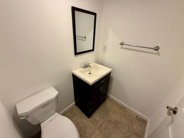 bathroom featuring toilet, baseboards, and vanity