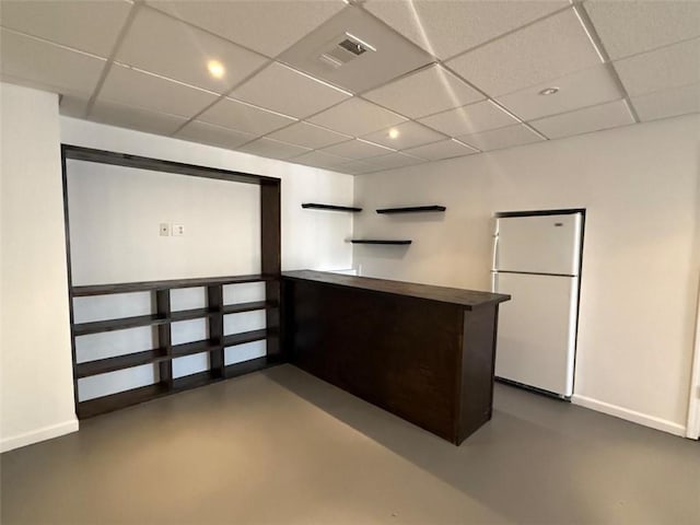 kitchen with freestanding refrigerator, visible vents, concrete floors, and baseboards