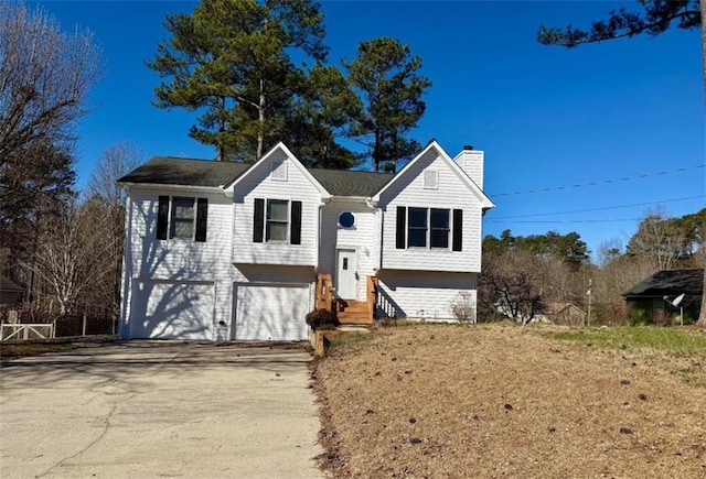 split foyer home with entry steps, concrete driveway, a chimney, and a garage