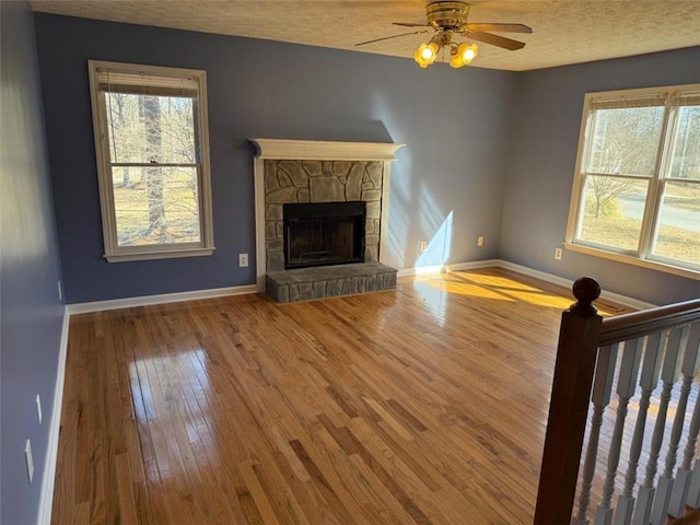 unfurnished living room featuring a healthy amount of sunlight, hardwood / wood-style flooring, and baseboards