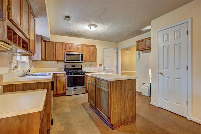 kitchen featuring light carpet, appliances with stainless steel finishes, a textured ceiling, sink, and a center island