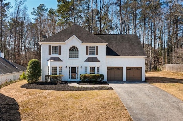 view of front of property with a garage, brick siding, driveway, and a front lawn