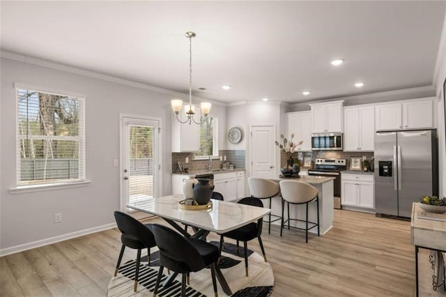 dining space with an inviting chandelier, plenty of natural light, ornamental molding, and light hardwood / wood-style floors