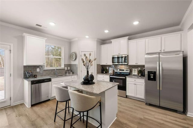 kitchen with white cabinetry, appliances with stainless steel finishes, a center island, and sink