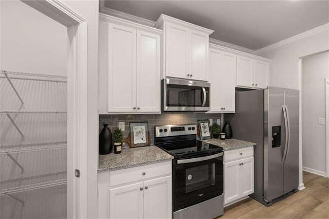 kitchen with crown molding, stainless steel appliances, light stone countertops, and white cabinets