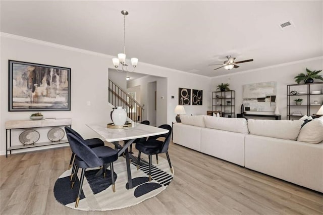 dining area featuring ornamental molding, ceiling fan with notable chandelier, and light hardwood / wood-style flooring