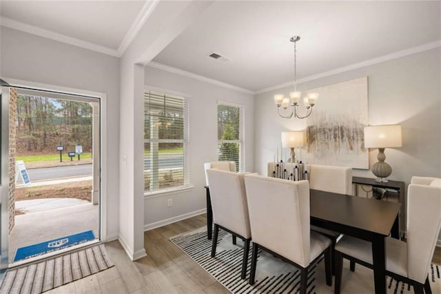 dining space featuring light hardwood / wood-style flooring, ornamental molding, and a chandelier