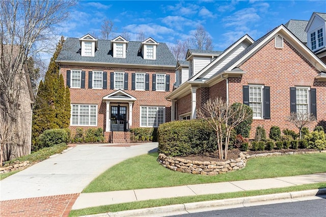 georgian-style home with brick siding and a front lawn