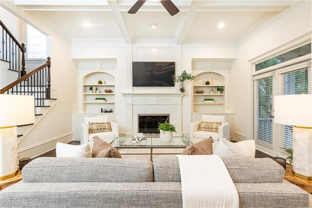 living room featuring built in shelves, coffered ceiling, stairway, beam ceiling, and crown molding