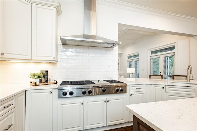 kitchen with a sink, white cabinetry, wall chimney exhaust hood, tasteful backsplash, and stainless steel gas stovetop