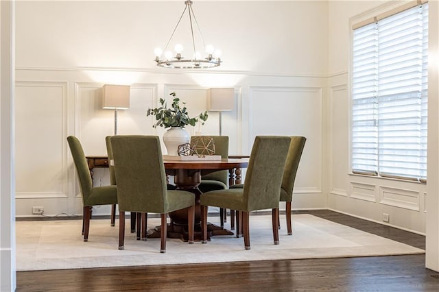 dining space with a notable chandelier, wood finished floors, and a decorative wall