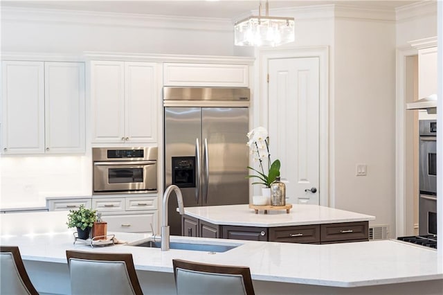 kitchen with white cabinets, a large island, decorative light fixtures, light countertops, and stainless steel appliances