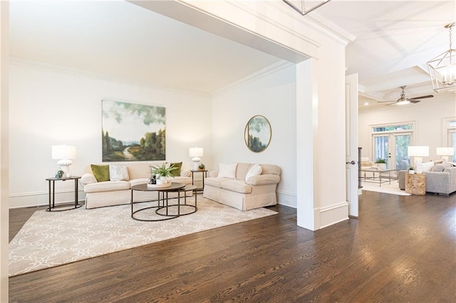 living room featuring dark wood-type flooring, a chandelier, crown molding, and baseboards