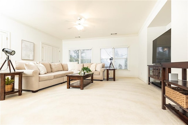 living area featuring visible vents, ornamental molding, a ceiling fan, and light colored carpet