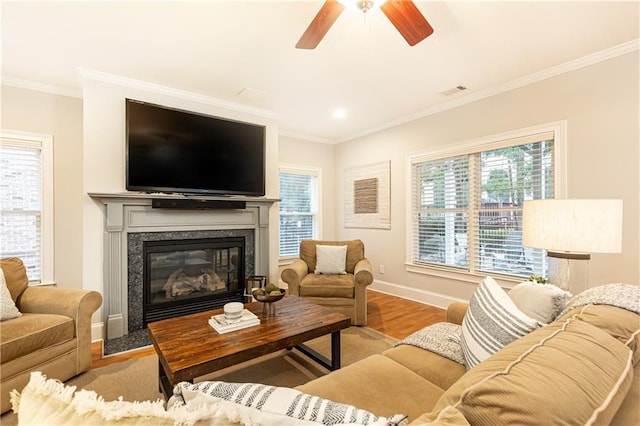 living area featuring ornamental molding, light wood-type flooring, and plenty of natural light