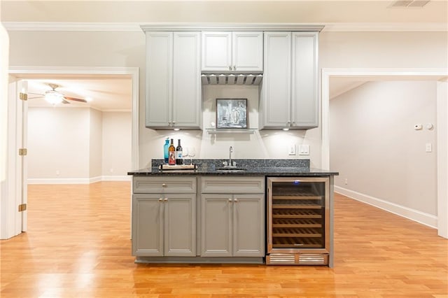 kitchen with crown molding, beverage cooler, a sink, and gray cabinets