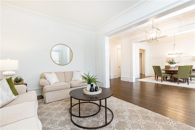 dining space featuring dark wood-style flooring, a decorative wall, an inviting chandelier, ornamental molding, and wainscoting