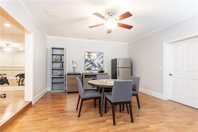 dining room featuring baseboards, crown molding, light wood finished floors, and ceiling fan