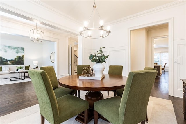 dining area featuring dark wood-style floors, a decorative wall, stairway, ornamental molding, and a chandelier